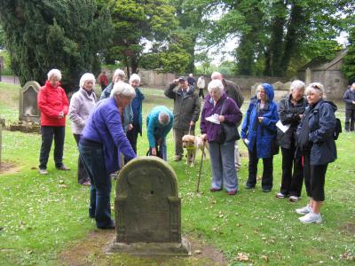 The Currie History Society peruse details on a headstone in Currie kirkyard